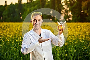 A young man biologist or agronomist examines the quality of rapeseed oil on a rape field. Agribusiness concept