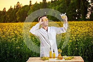 A young man biologist or agronomist examines the quality of rapeseed oil on a rape field. Agribusiness concept