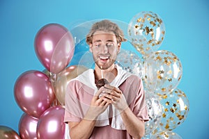 Young man with birthday muffin and air balloons