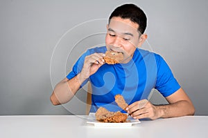 Young man biting fried chicken