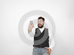 Young man with black beard is posing and looking at his smartphone in front of white background with different emotions