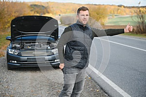 A young man with a black car that broke down on the road,copy space.