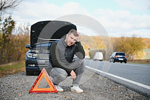 A young man with a black car that broke down on the road,copy space.