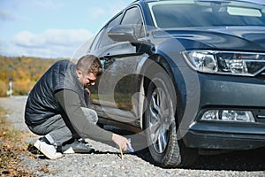 A young man with a black car that broke down on the road,copy space.