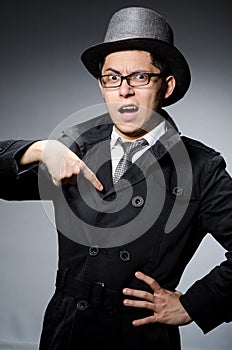 Young man in black coat and hat against gray