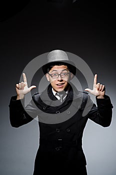 Young man in black coat and hat against gray