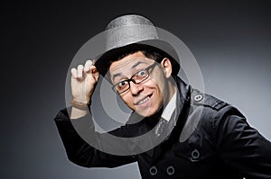 Young man in black coat and hat against gray