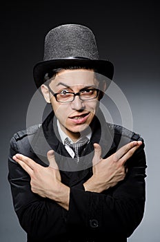 Young man in black coat and hat against gray