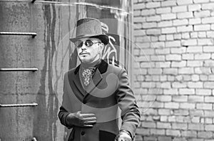 Young man in a black coat and top hat in the slums of the 19th century, steam punk