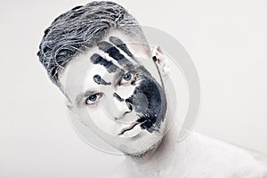 Young man with black hand print on white face. Closeup Portrait. Professional Fashion Makeup. fantasy art makeup