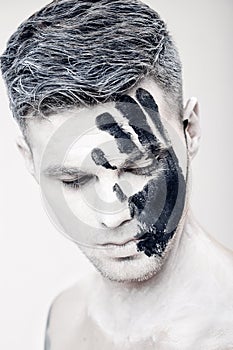 Young man with black hand print on white face. Closeup Portrait. Professional Fashion Makeup. fantasy art makeup