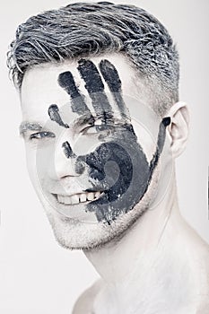 Young man with black hand print on white face. Closeup Portrait. Professional Fashion Makeup. fantasy art makeup