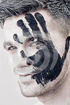 Young man with black hand print on white face. Closeup Portrait. Professional Fashion Makeup. fantasy art makeup