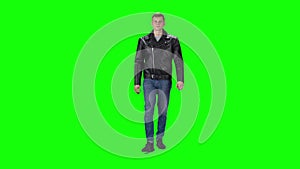 Young man in black leather jacket, jeans and sneakers going against a green background. Slow motion.