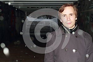 Young man in black stands in small tunnel at winter night