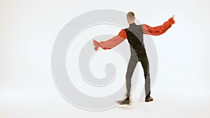 A young man in a black suit is dancing on a white background.