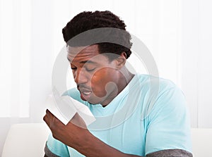 Young man blowing his nose in a tissue