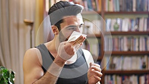 Young man blowing nose with handkerchief