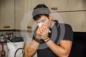 Young Man Blowing Nose into Tissue