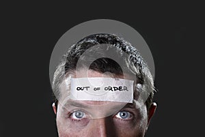 Young man with blue eyes and tape text out of order on forehead in dry empty mind