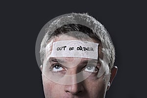 Young man with blue eyes and tape text out of order on forehead in dry empty mind