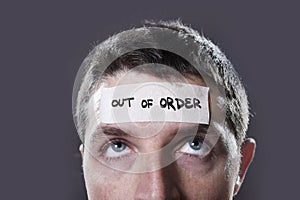 Young man with blue eyes and tape text out of order on forehead in dry empty mind