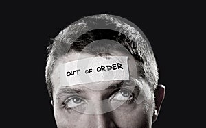 Young man with blue eyes and tape text out of order on forehead in dry empty mind photo