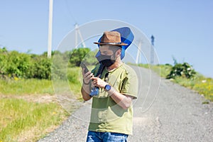 Young man with blue guitar and black protective mask doing call in the field