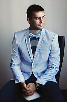 Young man in blue jacket with a white bow tie waits