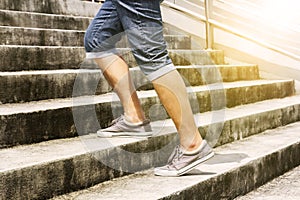 Young man in blue jeans and sneaker shoes walking up stairs outd