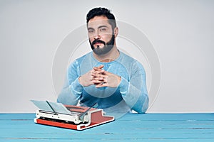 Young man in blue pullover standing holding retro typewriter