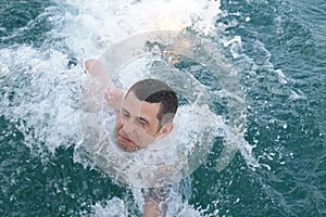 Young man in the blue sea struggling with the waves