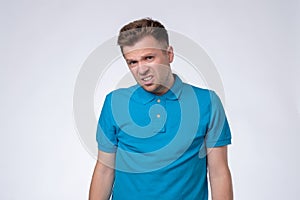 Young man in blue t-shirt aggressively bares his teeth