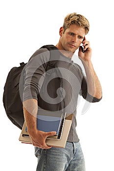 Young man with books and backpack on cell phone