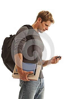 Young man with books and backpack on cell phone