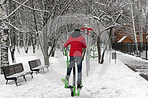 Young man borrows on an exercise bike in the open air in the park in winter.