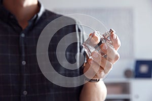 Young man with bottle of perfume indoors