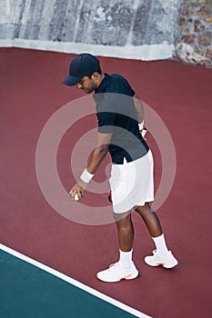 Young man bouncing the ball at the baseline