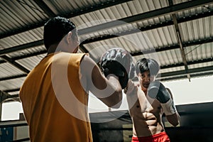 young man boxer doing exercise hitting punching competing with his trainer