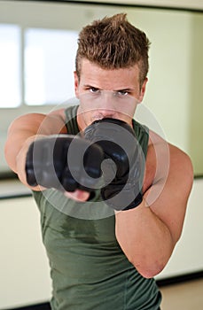 Young man with boxer's gloves throwing punch towards camera