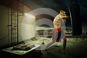 Young man boxing training , on top of the house above the city