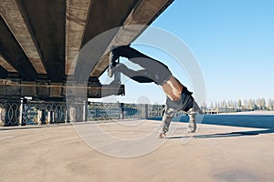 Young man break dancer doing somersault acrobatic stunts dancing on urban background