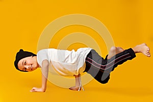 Young man break dancing hat and white t-shirt posing on yellow background