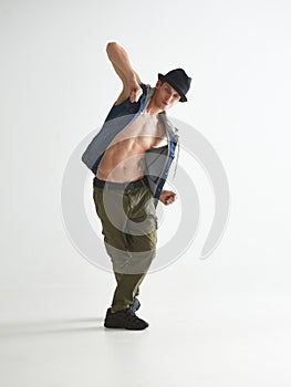 Young man breakdancer in hat dancing hip-hop in studio  on white background. Break dance lessons