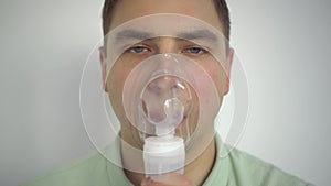 A young man breathes through an inhaler closeup. A man with an oxygen mask is being treated for a respiratory infection.