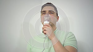 A young man breathes through an inhaler closeup. A man with an oxygen mask is being treated for a respiratory infection.