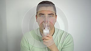 A young man breathes through an inhaler closeup. A man with an oxygen mask is being treated for a respiratory infection.