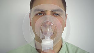 A young man breathes through an inhaler closeup. A man with an oxygen mask is being treated for a respiratory infection.