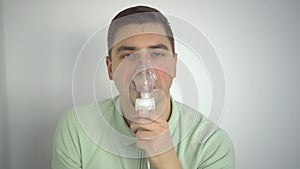 A young man breathes through an inhaler closeup. A man with an oxygen mask is being treated for a respiratory infection.