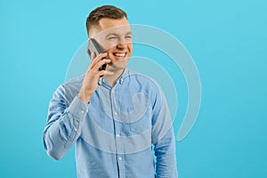 Young man in bright colorful wear talking on mobile cell phone on blue background. Trendy guy have conversation. Smartphone,